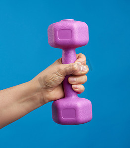 蓝色背景中，女手握着一个粉色塑料哑铃
