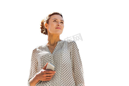 年轻漂亮的女人拿着智能手机站在办公楼前用镜头光晕的剪影