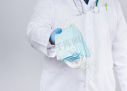 乳汁摄影照片_一件白色外套的医生，蓝色乳汁无菌手套拿着纺织品