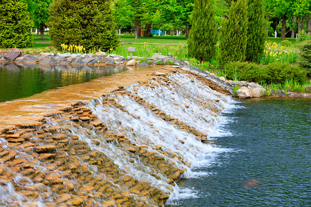 一个美丽的装饰瀑布的水流在夏季公园迅速流动。