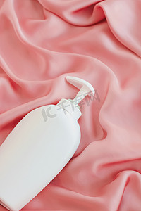 产品模型摄影照片_空白标签化妆品容器瓶作为粉红色丝绸背景上的产品模型