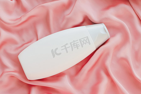 产品模型摄影照片_空白标签化妆品容器瓶作为粉红色丝绸背景上的产品模型