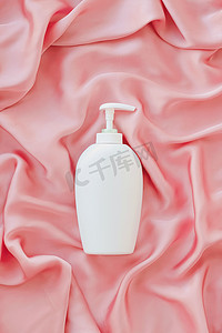 空白标签化妆品容器瓶作为粉红色丝绸背景上的产品模型