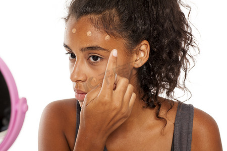深色皮肤摄影照片_深色皮肤的女人在脸上涂粉底液