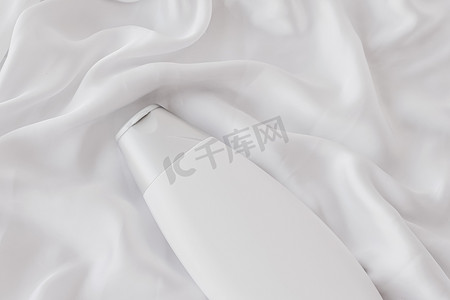 产品模型摄影照片_空白标签化妆品容器瓶作为白色丝绸背景上的产品模型