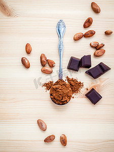 巧克力粉摄影照片_勺子中的棕色巧克力粉、烤可可豆和深色 c