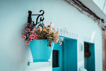 白墙上挂着蓝色桶里的粉色花，典型的地中海村庄