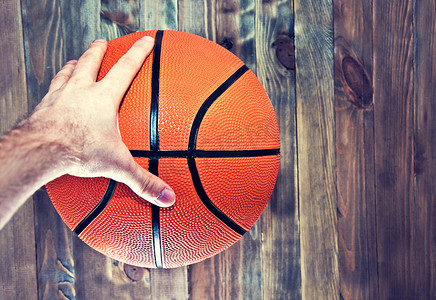 在用手抓取的木硬木地板上的篮球球。