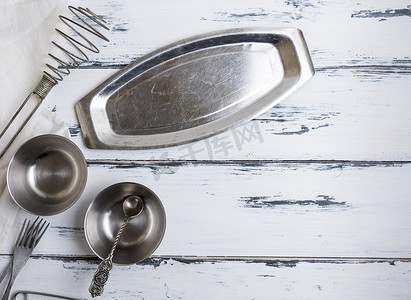 木质空托盘摄影照片_白色木质背景上的厨房空金属物品