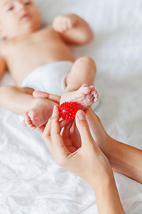 婴儿按摩小手摄影照片_妈妈抱着刚出生的婴儿的脚。
