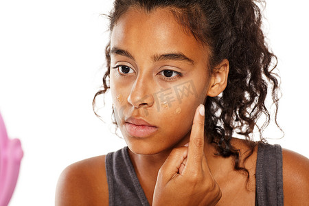 深色皮肤的女人在脸上涂粉底液