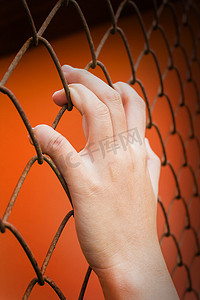 橙色背景中女性手抓铁棒，囚禁感