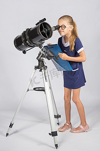 戴眼镜的年轻天文学家感兴趣地凝视着望远镜的目镜