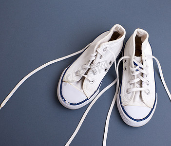 一双带解开鞋带的白色旧纺织运动鞋