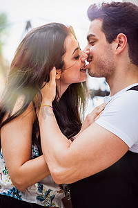 拥抱恩爱摄影照片_恩爱的情侣女孩亲吻并咬着男友的嘴唇。