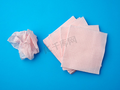 蓝色背景上皱巴巴的粉色纸一次性餐巾
