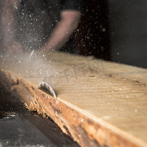 一个人在细木工场用圆锯切割木头