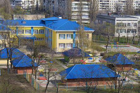 灰色城市高层建筑背景下的幼儿园亮蓝色屋顶