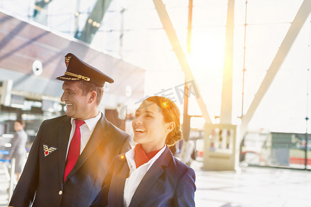 成熟的飞行员和迷人的空姐在机场微笑着走路的肖像