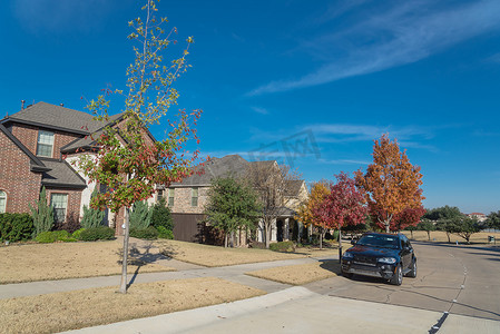 美国德克萨斯州达拉斯市外色彩缤纷的秋季街道上停着汽车的新郊区房屋的典型前廊入口