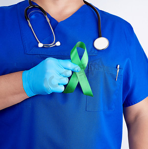 乳汁摄影照片_蓝色制服和乳汁手套的医生拿着一条绿色丝带