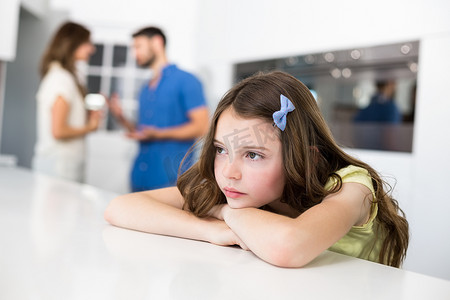 悲伤的女孩靠在桌子上反对父母争吵