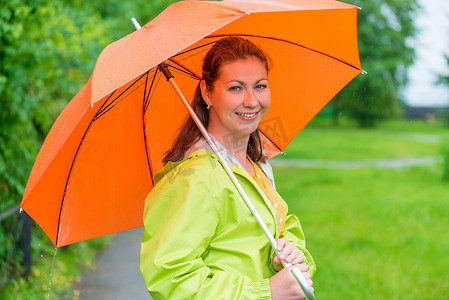 30岁微笑的女孩在雨中撑着伞