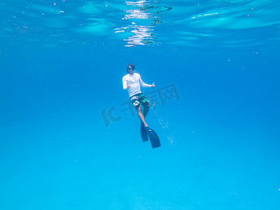 在蓝色海洋中自由潜水的人的水下视图。