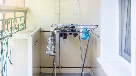 金属晾衣架站在阳台上，湿衣服在夏日晾干并挂在烘干机上