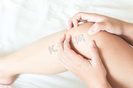 黑色膝盖摄影照片_特写女性手握膝盖，床上疼痛，保健和