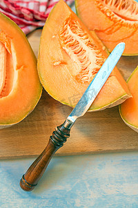 质朴的木桌上的甜瓜瓜片和刀