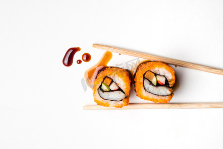 寿司、日本食品、加州卷用筷子和酱汁在白色背景上。