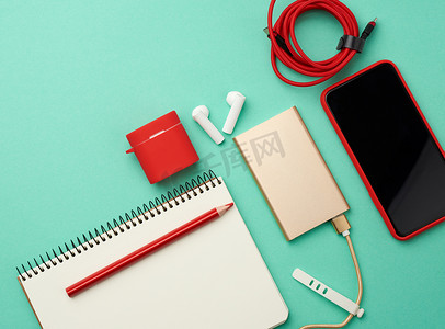 纸质笔记本、带电缆的移动电源、带空白的红色智能手机