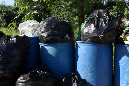 垃圾袋塑料袋摄影照片_垃圾桶，垃圾袋，满垃圾箱废塑料袋，垃圾袋黑色全和蓝色坦克垃圾箱，污染垃圾塑料垃圾