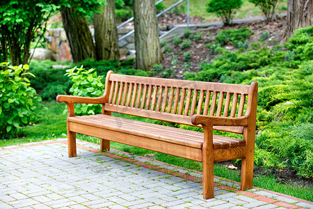 一个美丽而优雅的橡木长凳矗立在铺路板上休闲区的公园里。