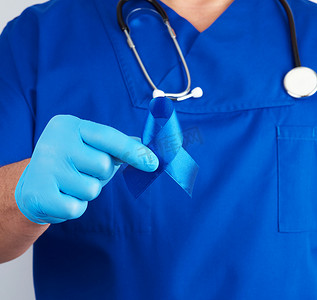 深蓝色蓝色摄影照片_穿着蓝色制服和无菌乳胶手套的医生拿着深蓝色