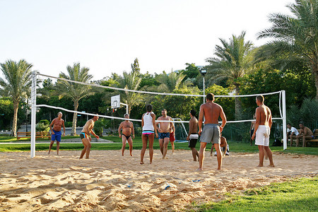 汗流浃背摄影照片_度假村海滩上的人们打排球