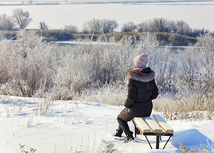 在一个阳光明媚的冬日，一位年轻女子坐在木凳上，看着平静的南布格河。
