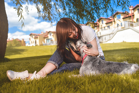 狗和人玩耍摄影照片_白人快乐的女人在公园里和她心爱的狗玩耍。
