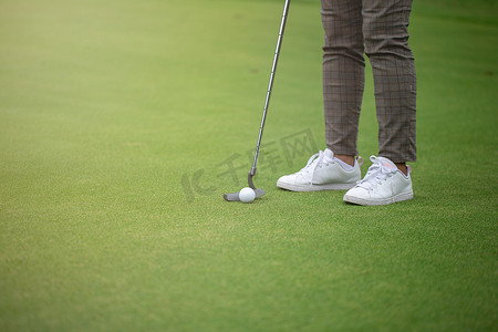 高尔夫球手穿上果岭和靠近洞的高尔夫球。