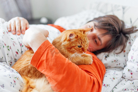 男人和宠物摄影照片_男人和姜猫在床上。