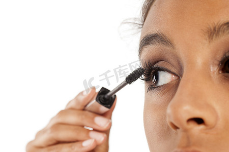 深色皮肤的女人在她的睫毛上涂睫毛膏