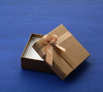 打开棕色方形纸板空盒子，物品放在蓝色木头上