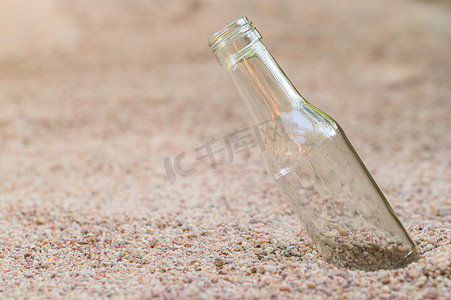沙子上的空玻璃瓶 垃圾污染的概念