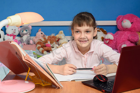 孩子们房间里的女孩微笑着坐在书桌前做作业