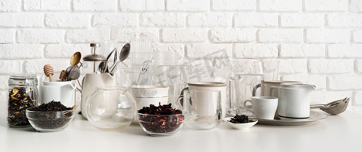 陶瓷器皿摄影照片_白砖墙背景桌上的陶瓷和玻璃杯和餐具