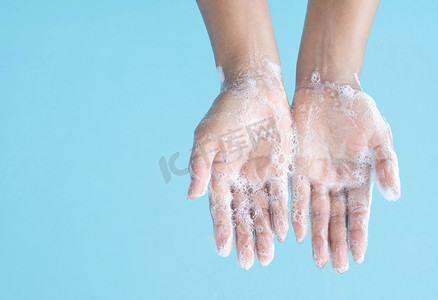 上洗手摄影照片_特写女人的手在蓝色背景上用肥皂洗手，健康