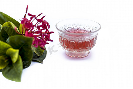 黄色五角星边框摄影照片_红色五角花或埃及星花或茉莉花在白色上的特写，其提取的草药和药用茶放在一个小透明玻璃碗中。