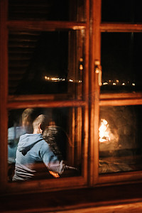 男人和女孩坐在燃烧的壁炉的背景上