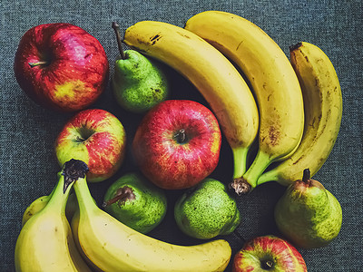 香蕉梨摄影照片_乡村亚麻布背景中的有机苹果、梨和香蕉
